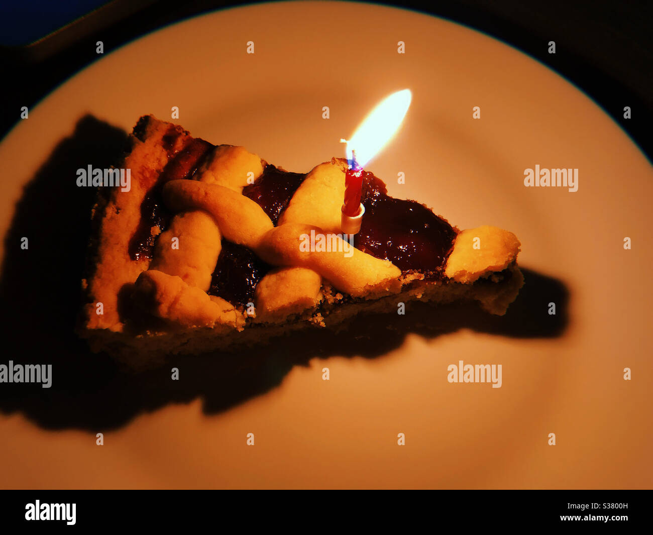 Eine Scheibe hausgemachter Beeren Crostata und Kerze Stockfoto