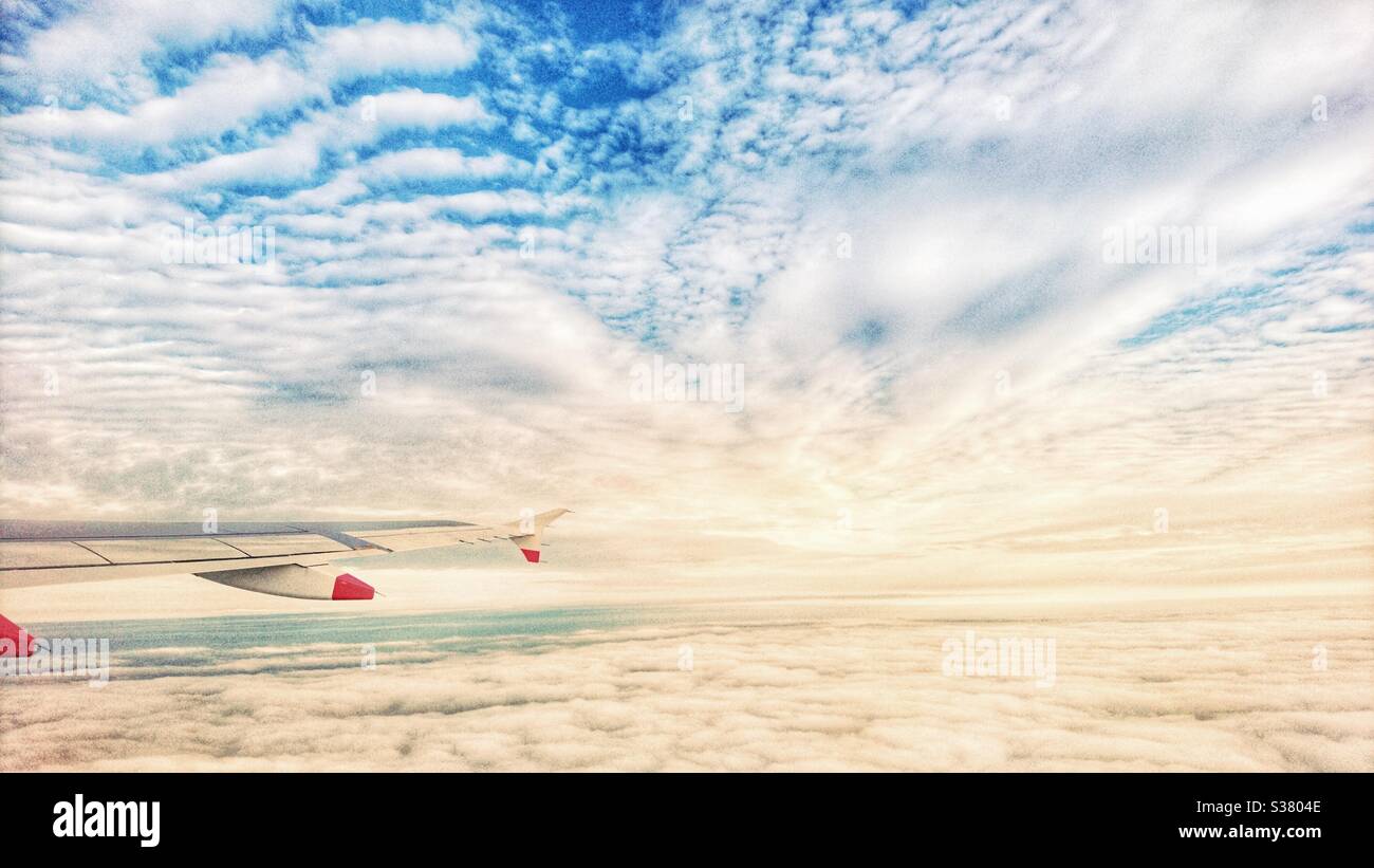 Ein Foto aus dem Flugzeug, das über den Flügel über Wolken blickt. Reisen, Urlaubsziel Foto. Stockfoto