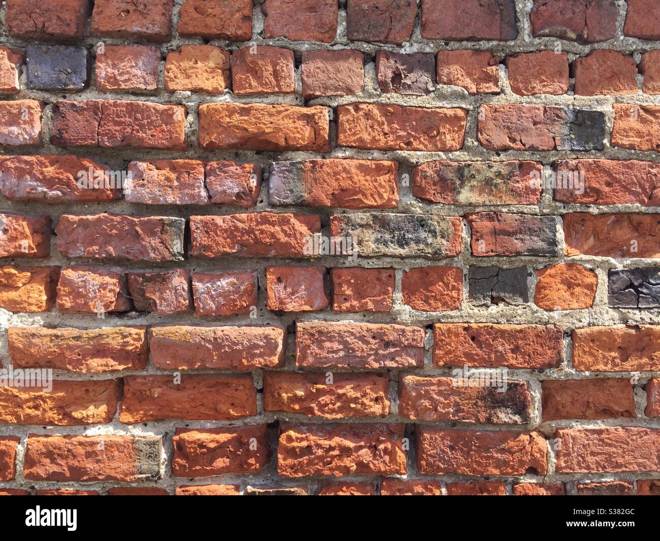 Ein abgenutzter und verwitterter roter Backsteinwand-Hintergrund mit Kopierraum - Smartphone-aufgenommenes Stockfoto