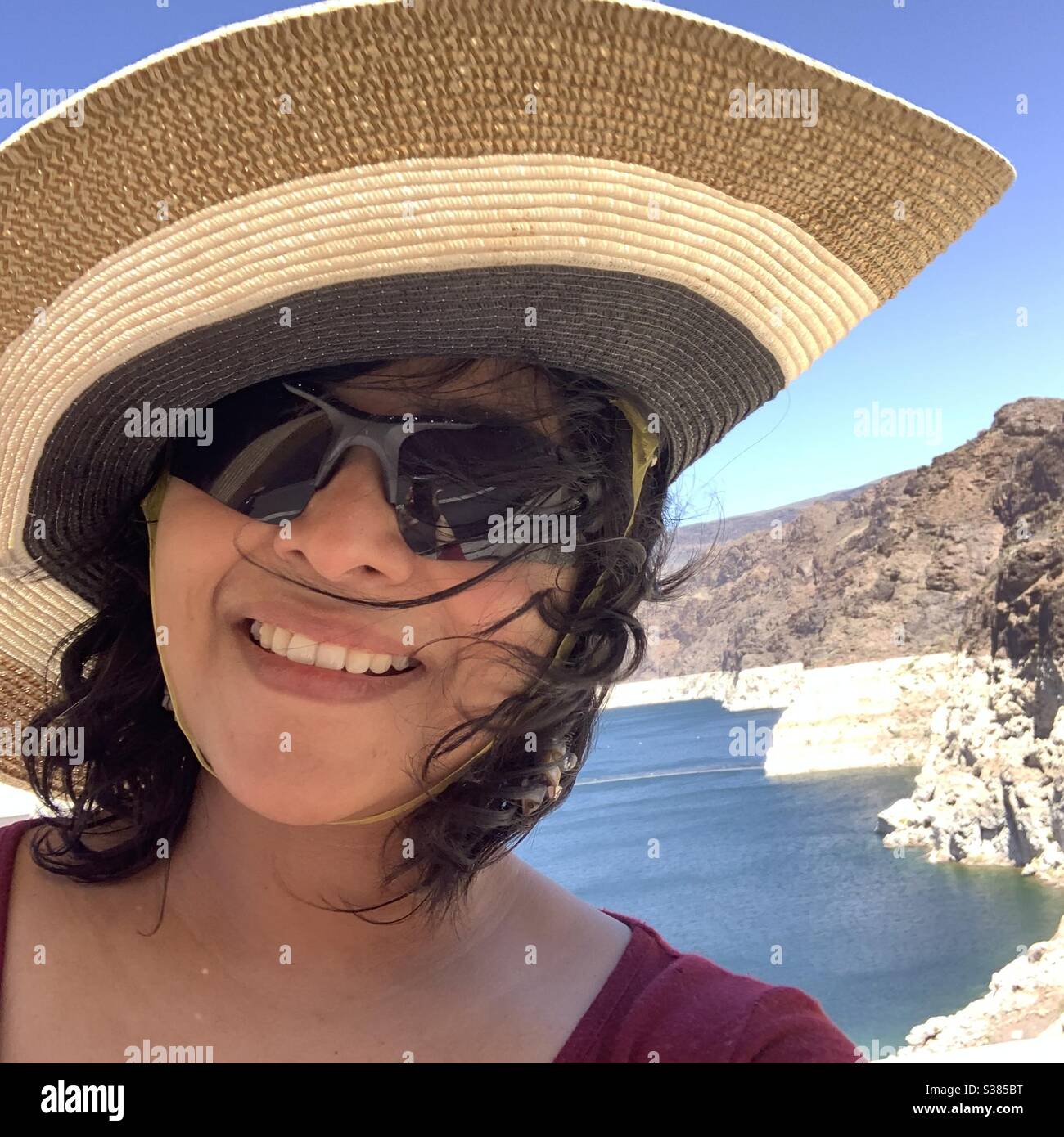 Hübsche Frau mit Hut mit Wind geblasen Haar vor blauen See Stockfoto