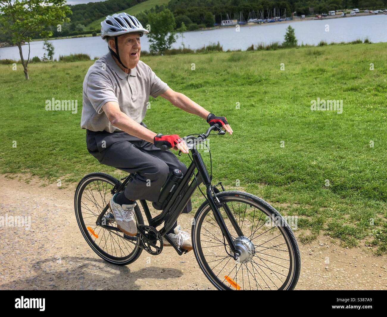 Älterer Mann mit Demenz fährt mit einem eBike an einem See Rother Valley Sheffield South Yorkshire - Smartphone-aufgenommenes Stockfoto