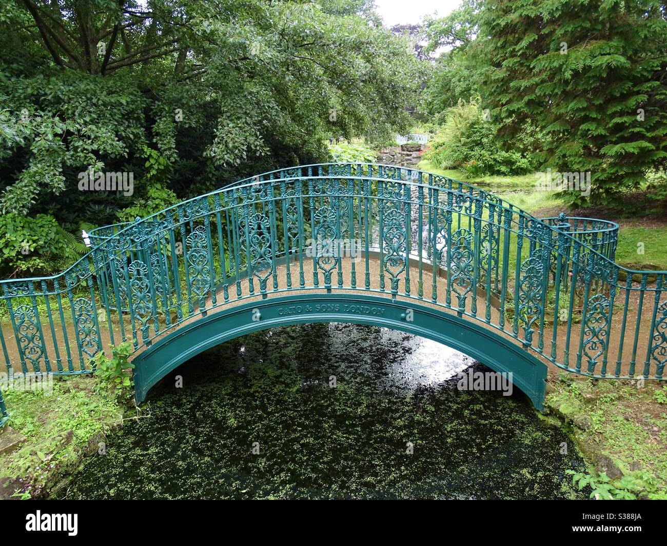 Grüne verzierte Brücke über einen Fluss in einem Park in England Stockfoto