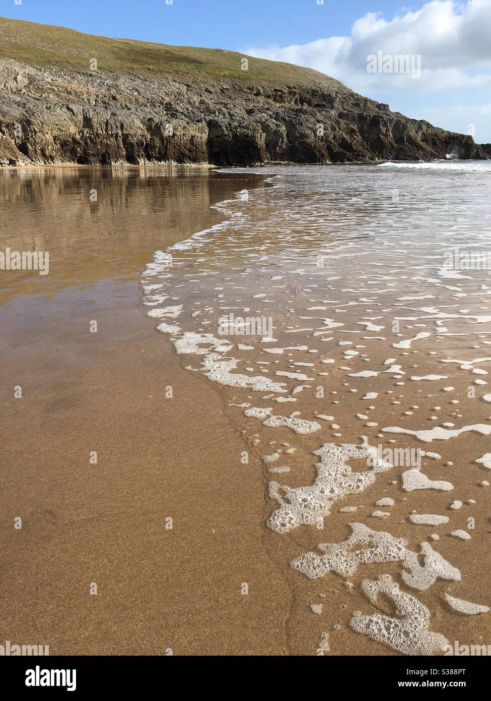 Sandige Küste mit Meeresfluten an der Gezeitenlinie des Sandstrandes - Smartphone-aufgenommenes Stockfoto