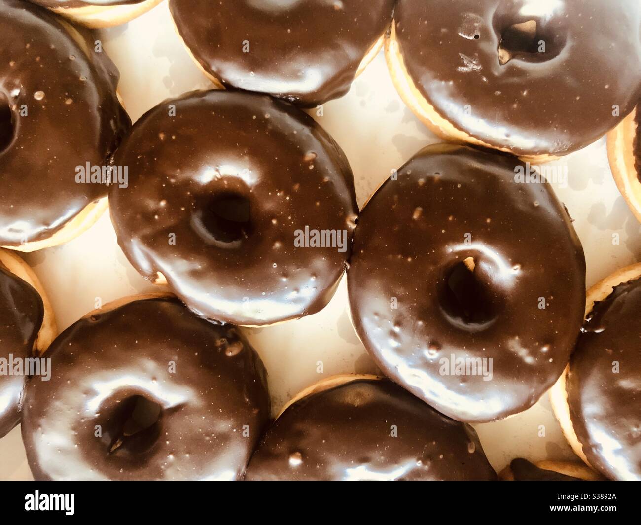 Draufsicht auf einen Rahmen von Schokolade überzogenen Donuts in einer weißen Box Stockfoto