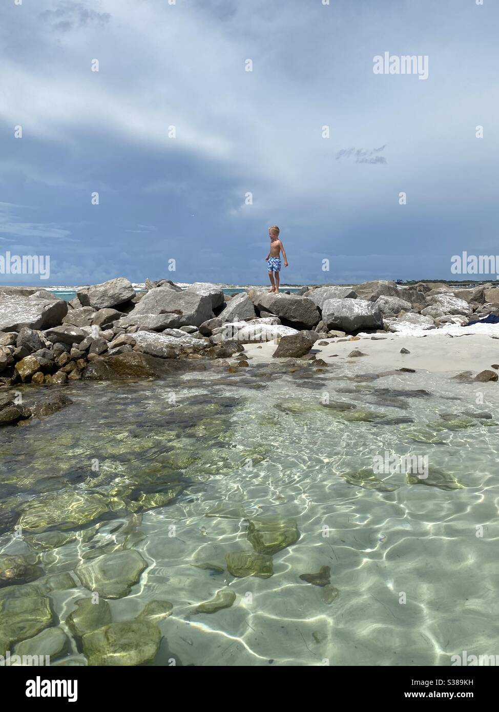 Kleiner Junge, der am Strand an der felsigen Küste spielt Stockfoto