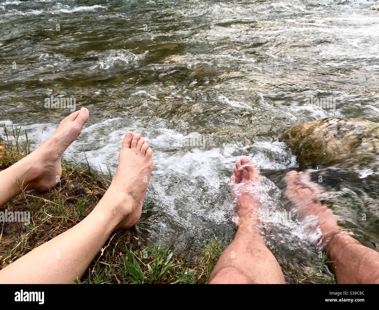 Zwei Menschen kühlen ihre Füße in einem Fluss - Smartphone-aufgenommenes Stockfoto