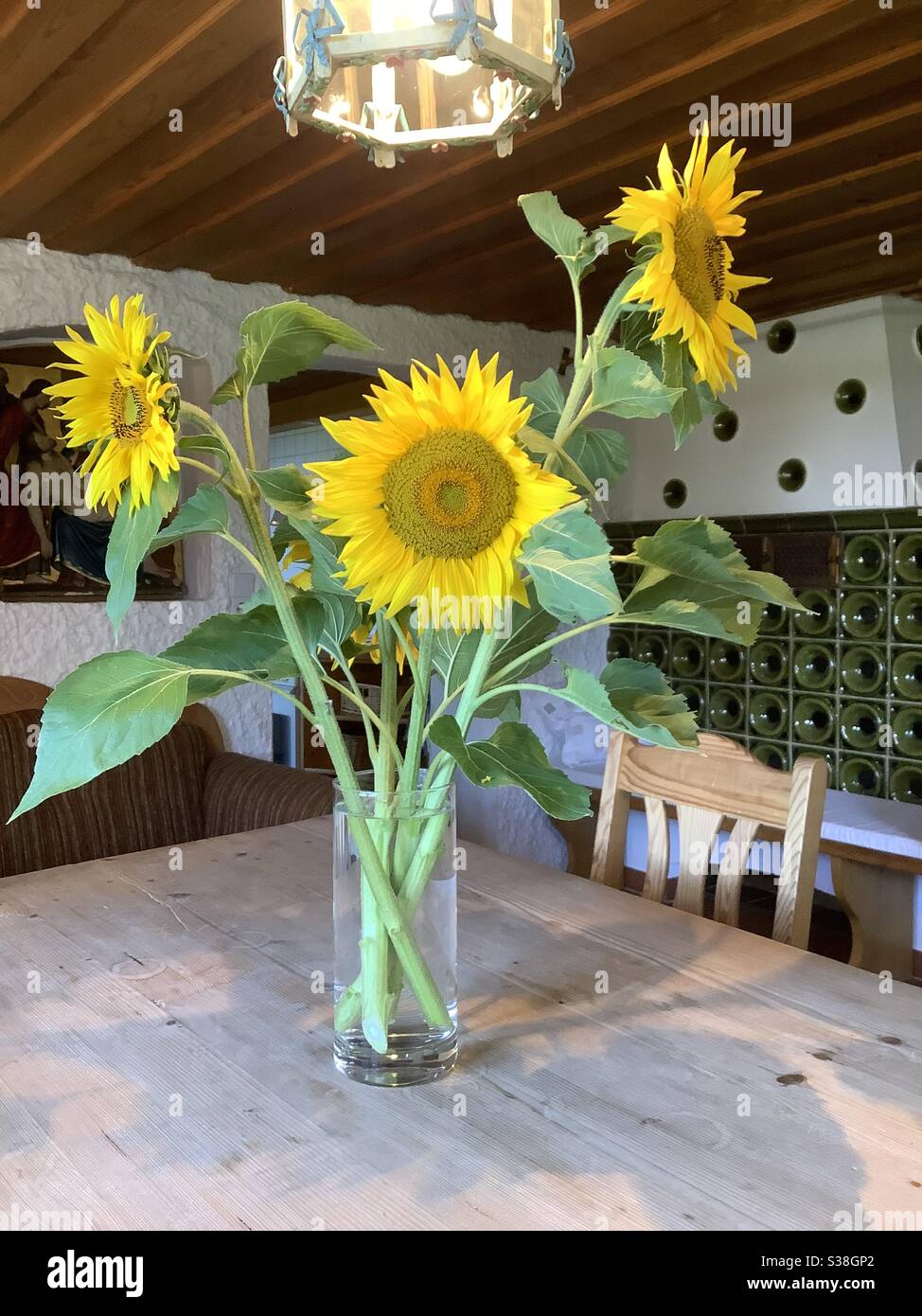 Vase mit geernteten blühenden Sonnenblumen auf Holztisch im alten bayerischen Bauernhaus Stockfoto
