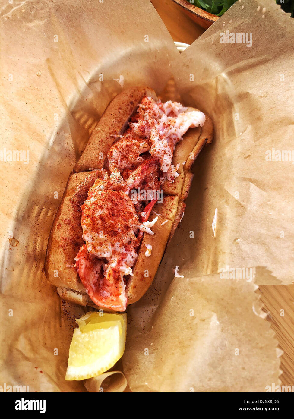 Hummerrolle im Korbkorb mit Zitronenkeil im Restaurant - Smartphone-aufgenommenes Stockfoto