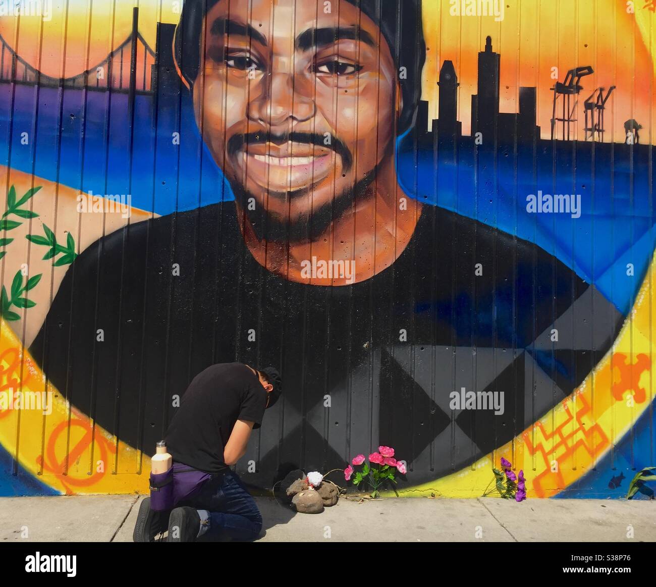 Mann, der an Alter und Wandbild zu Oscar Grant an der Fruitvale BART Station betet, wo Oscar von einem Polizisten getötet wurde. - Smartphone-aufgenommenes Stockfoto