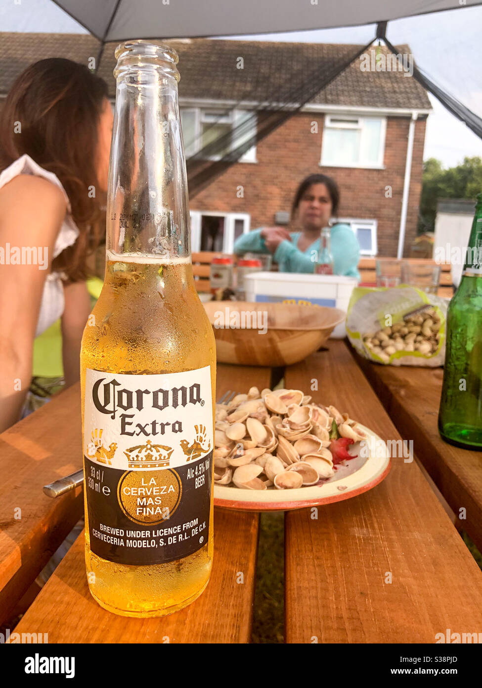 Bier trinken und Pistazien essen draußen im Garten mit Freunden. - Smartphone-aufgenommenes Stockfoto