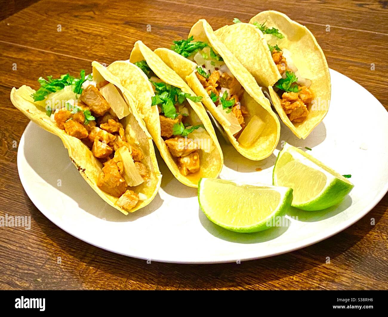 Mexikanisches Essen, Pastor Tacos mit Koriander, Zwiebel und Limette auf einem weißen Teller. Stockfoto