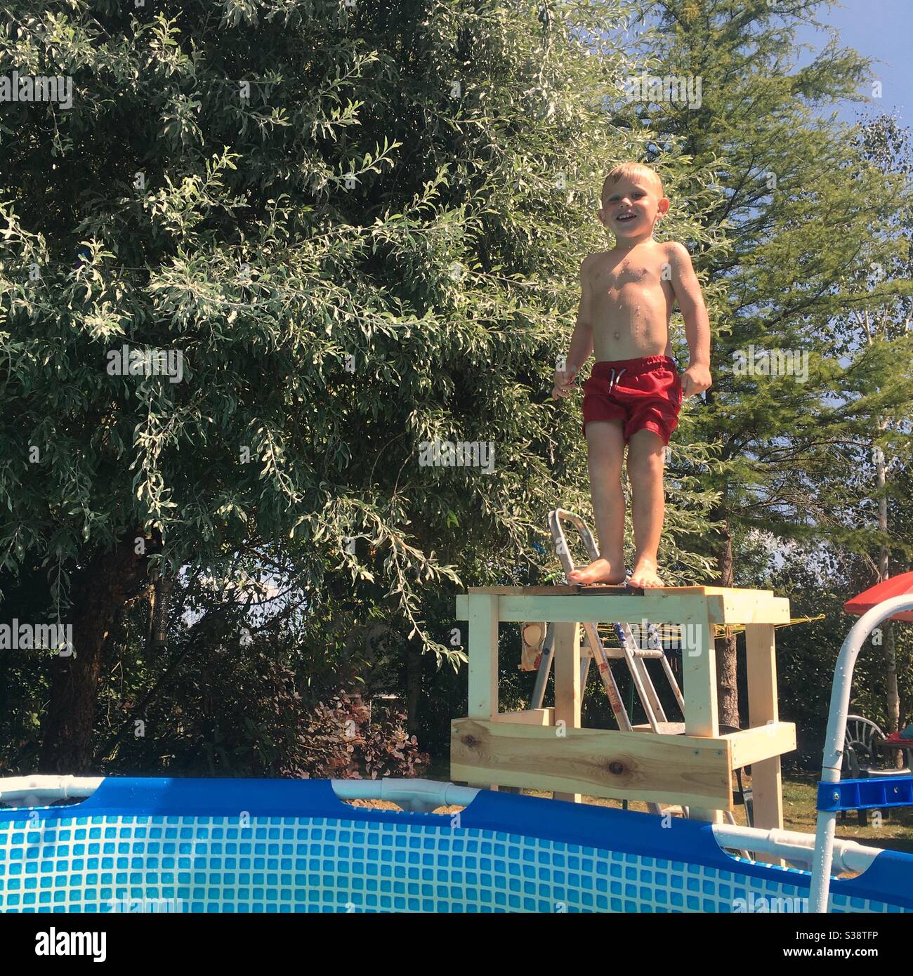 Dreijähriger Junge, der während einer Hitzewelle in einen Pool springt, Hampshire, England, Großbritannien. Stockfoto