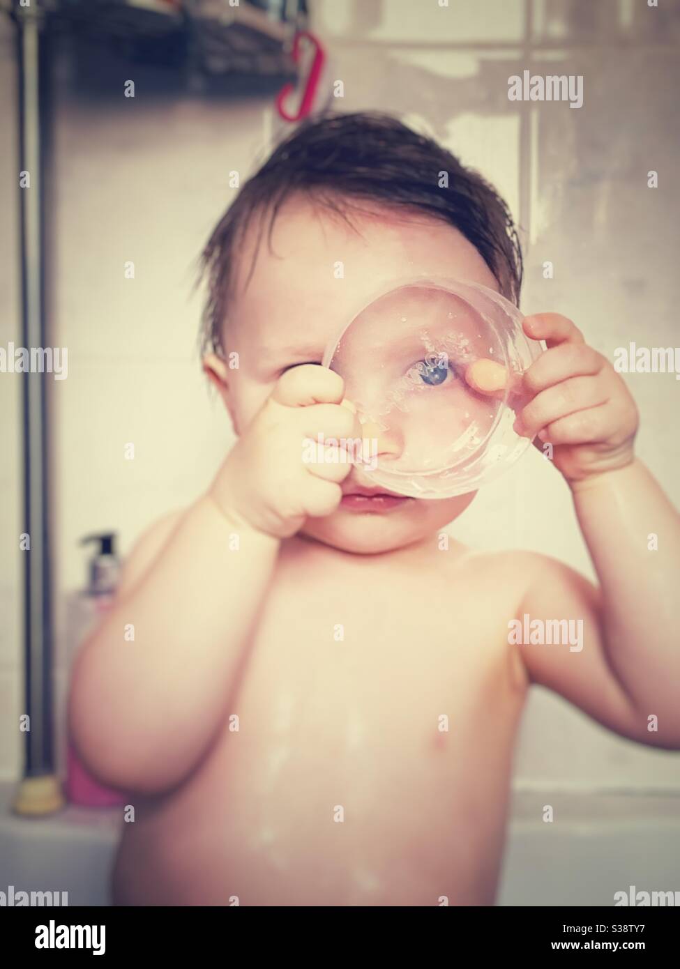 Baby Boy spielt in der Badewanne mit einem Plastikbehälter Deckel. Stockfoto