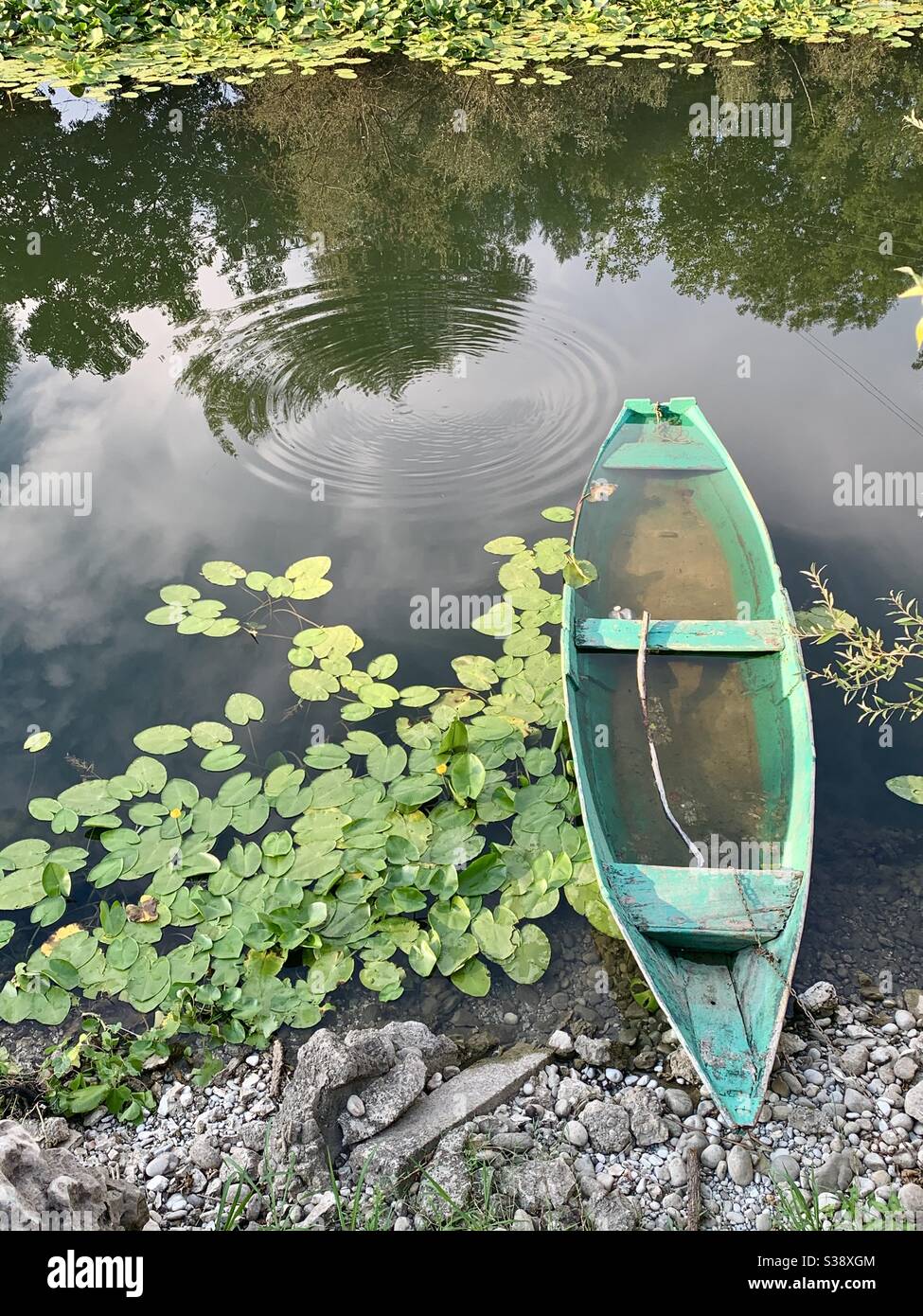 Gebrochenes überflutetes grünes Boot auf dem Fluss mit Seerosen Stockfoto