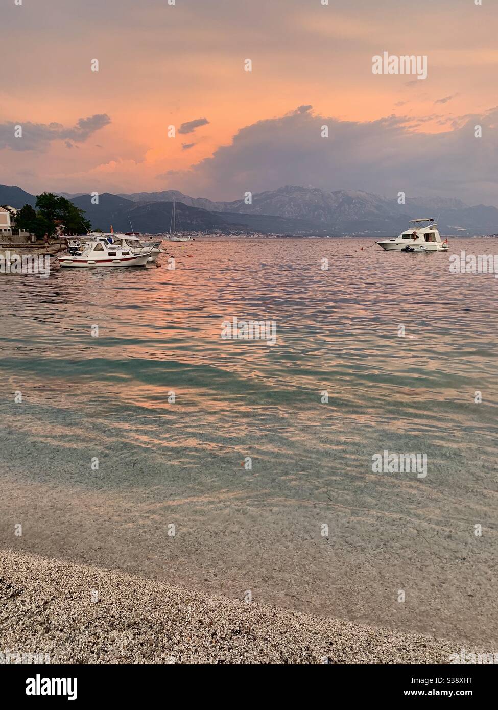 Boote, die bei Sonnenuntergang am Strand von Djenovici im Meer schwimmen Montenegro Stockfoto