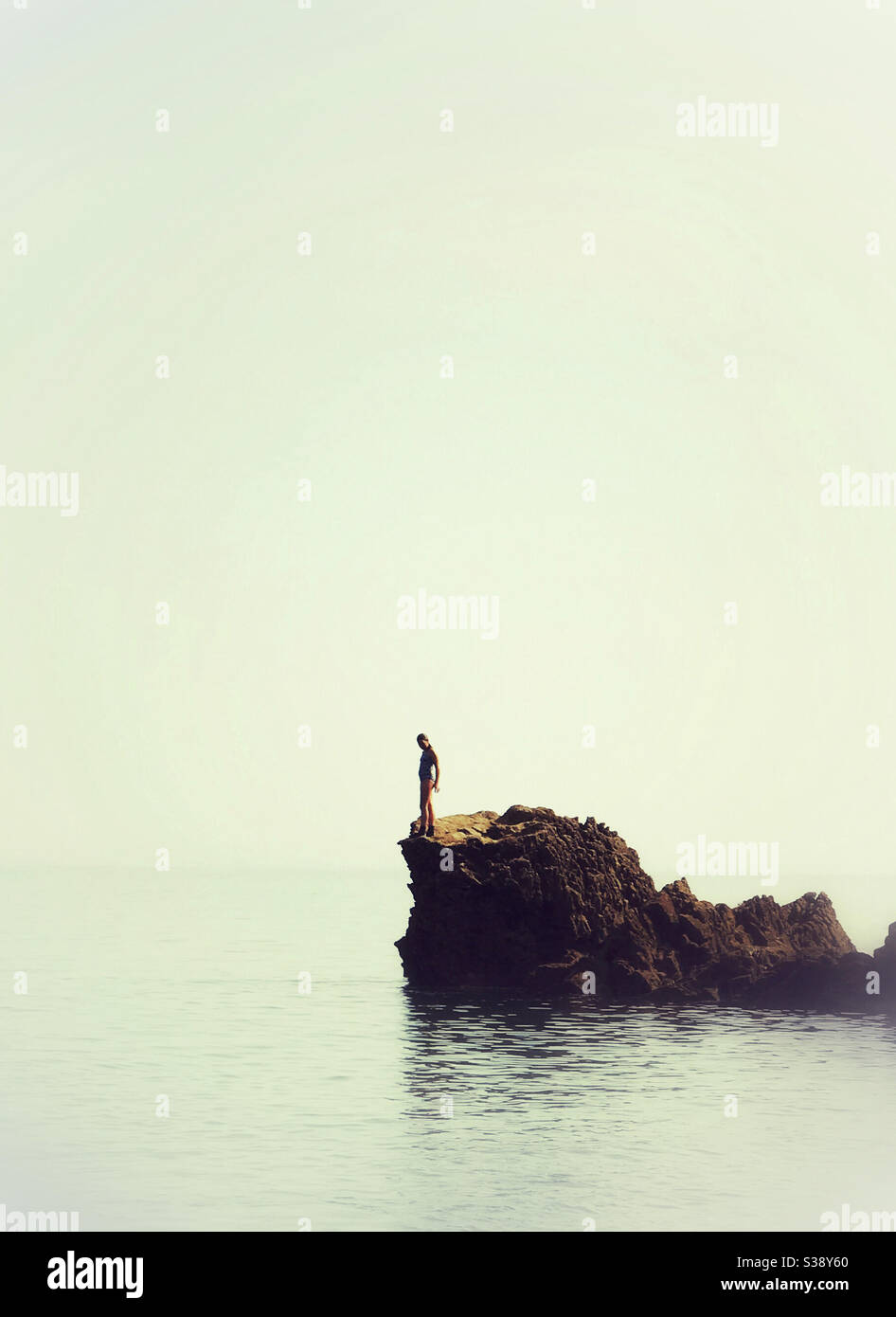 Ein Mädchen auf einem Felsen im Begriff, in die springen Meer Stockfoto