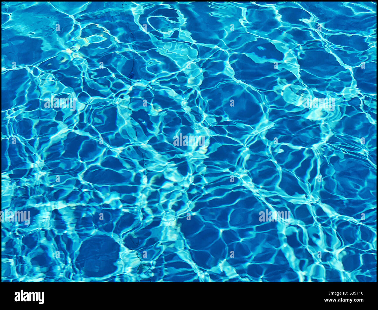 Das Wasser in einem Schwimmbad plätschelt durch die helle Sonne. Ein geheimnisvolles, aber Interessantes Bild von klarem „blauem“ Wasser. Bildnachweis - ©️ COLIN HOSKINS. Stockfoto