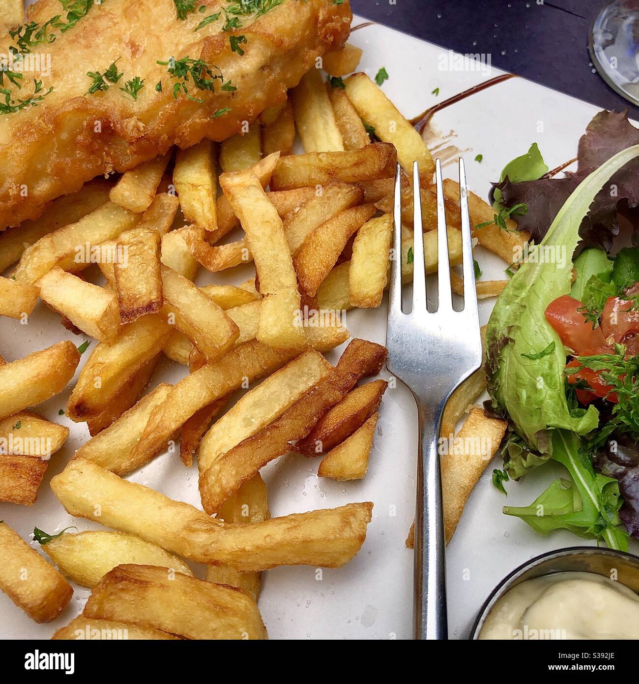 Auf halbem Weg durch einen Teller mit Fisch und Chips. - Smartphone-aufgenommenes Stockfoto