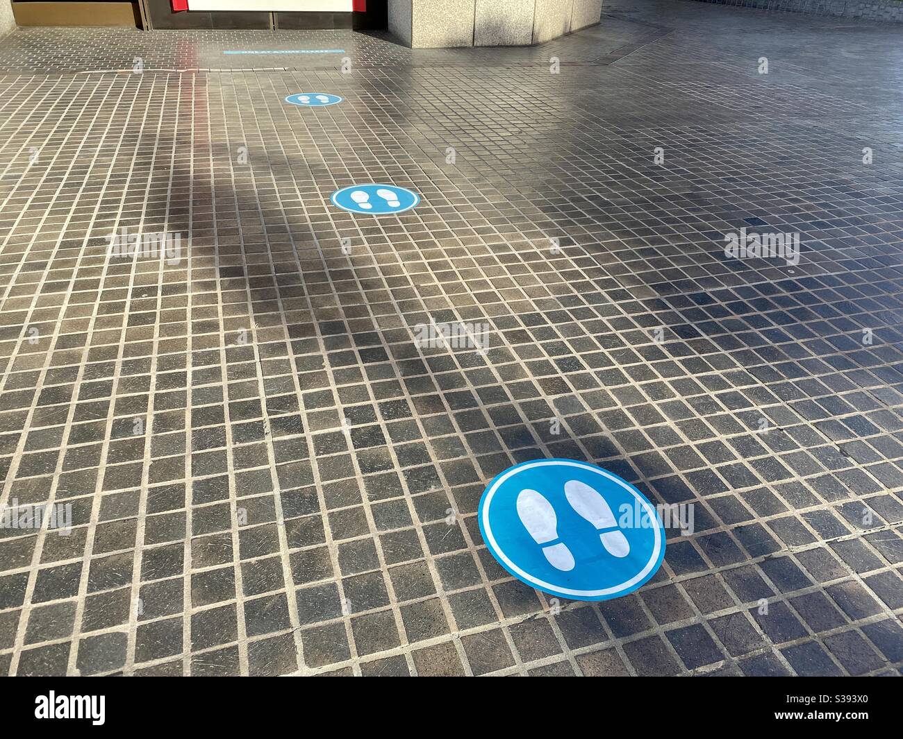 LOS ANGELES, CA, JUN 2020: Blaue Bodenschilder mit Fußabdrücken weisen auf 6-Fuß-soziale Distanzierungsregeln während der Covid-19-Viruspandemie hin - Smartphone-aufgenommenes Stockfoto