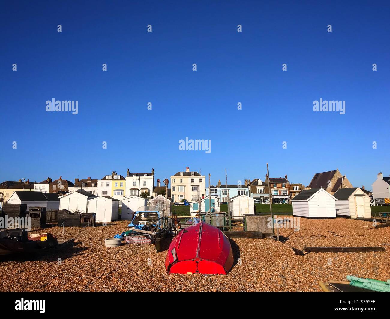 Rotes Fischerboot, das kopfüber am Strand festgemacht hat Walmer Deal Großbritannien - Smartphone-aufgenommenes Stockfoto