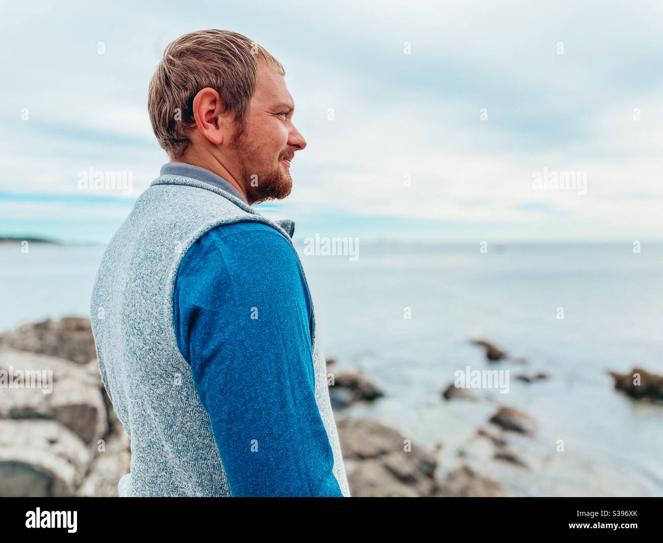 Mann, der entlang einer felsigen Küste in die Ferne blickt Stockfoto