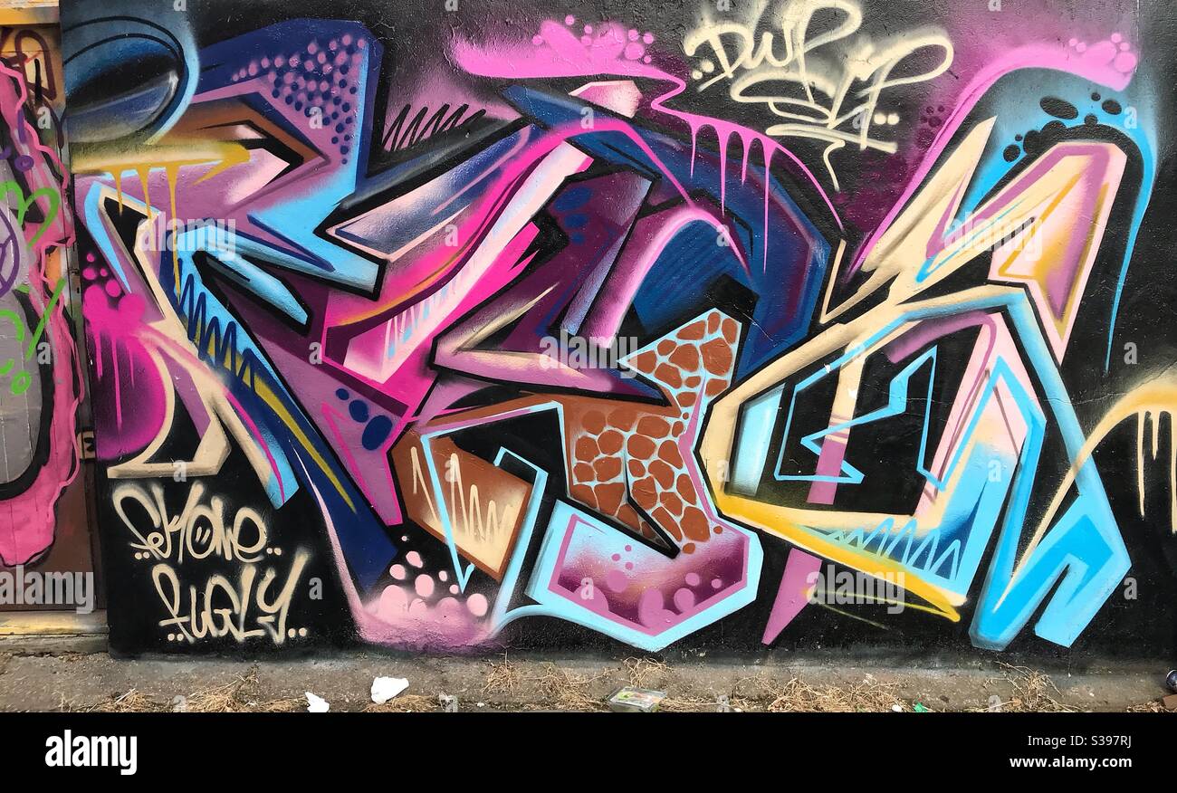 Stilisierte Graffiti lila und rosa an der Steinwand in Brighton VEREINIGTES KÖNIGREICH - Smartphone-aufgenommenes Stockfoto