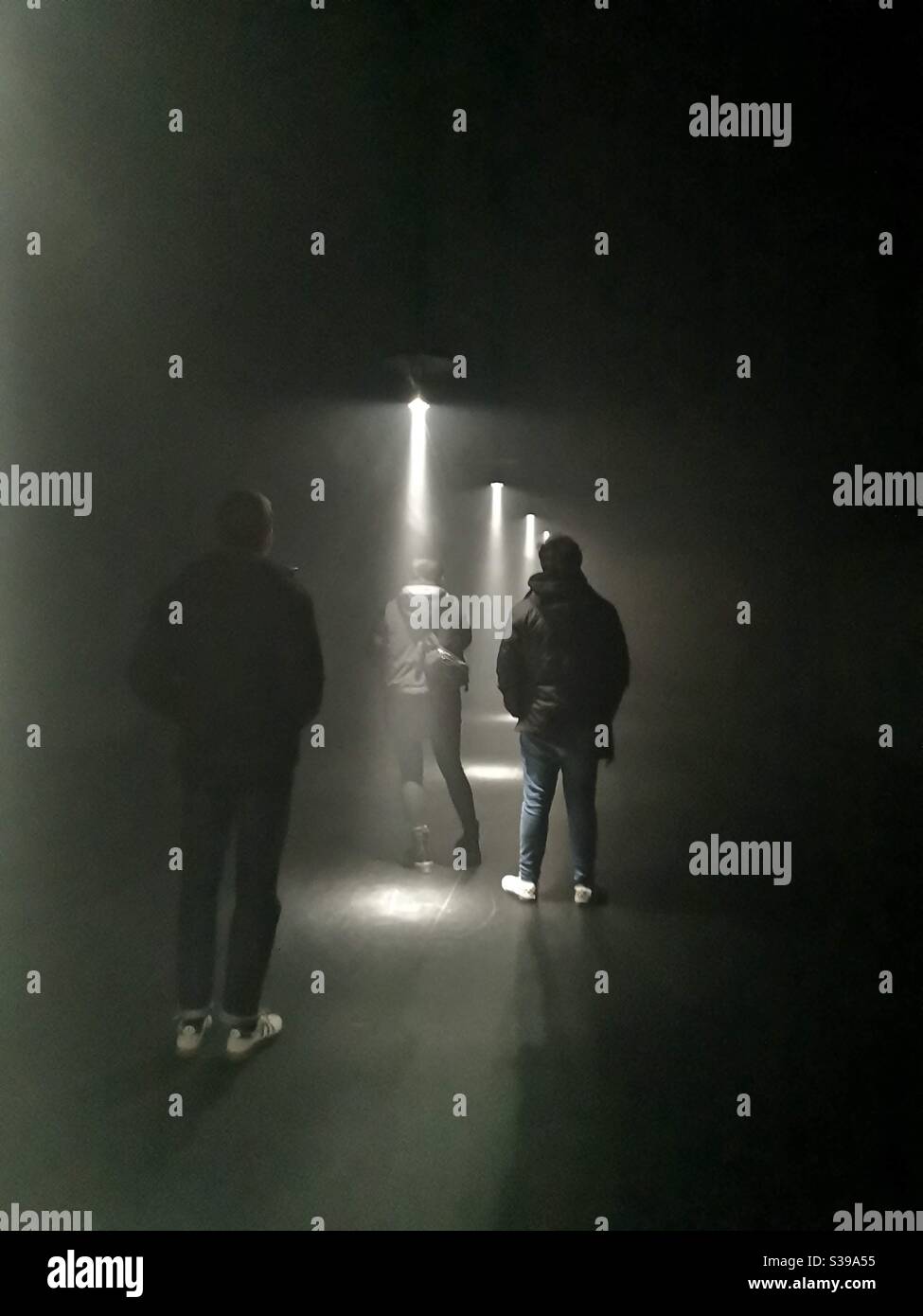Menschen im Dunkeln und Lichtstrahlen bei Mira Calix Ausstellung in London Stockfoto