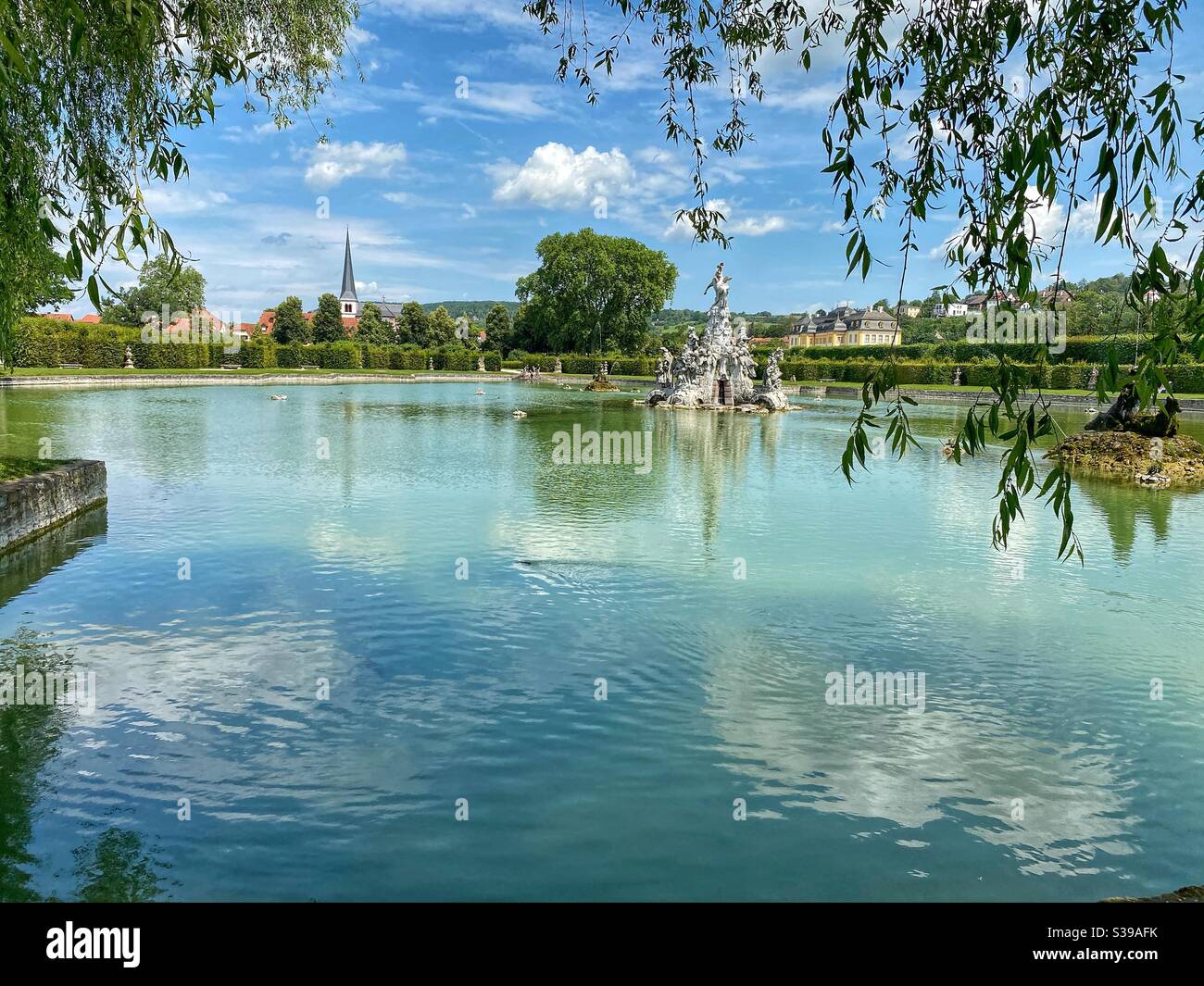 Teich mit Wolkenreflexen im Rokokogarten in Sommerresidenz bei Würzburg. Stockfoto