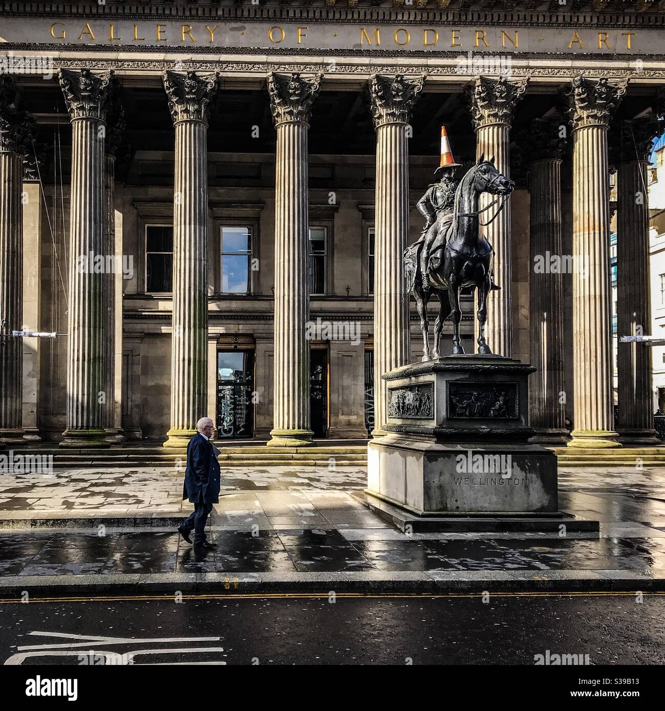 Mann, der an der Statue des Duke of Wellington in Glasgow vorbeigeht - Smartphone-aufgenommenes Stockfoto