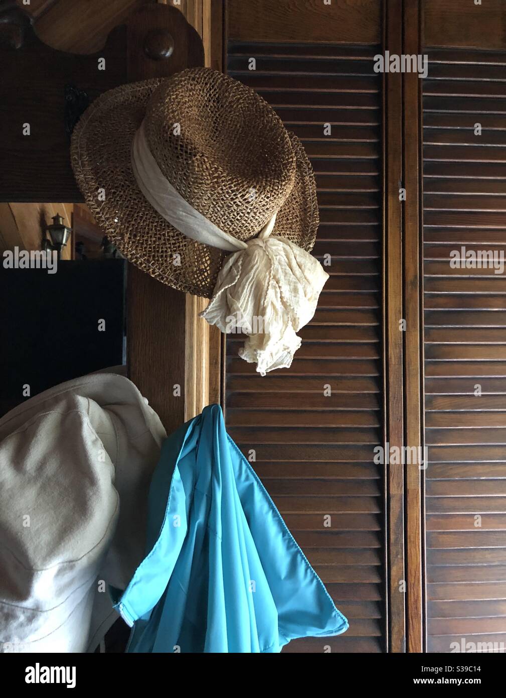 Zwei Hüte und eine Jacke hängen im Eingangsbereich auf antik Hallenbaum beleuchtet mit natürlichem Licht aus dem Fenster - Smartphone-aufgenommenes Stockfoto