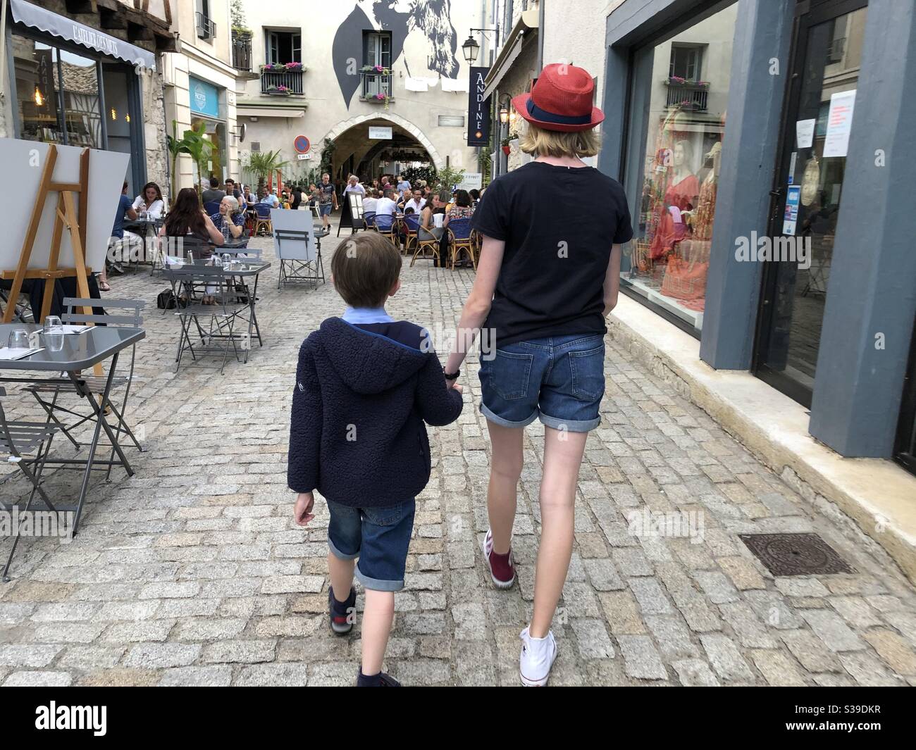 Zwei Kinder spazieren durch die mittelalterliche Bastide-Stadt Eymet In Frankreich - Smartphone-aufgenommenes Stockfoto