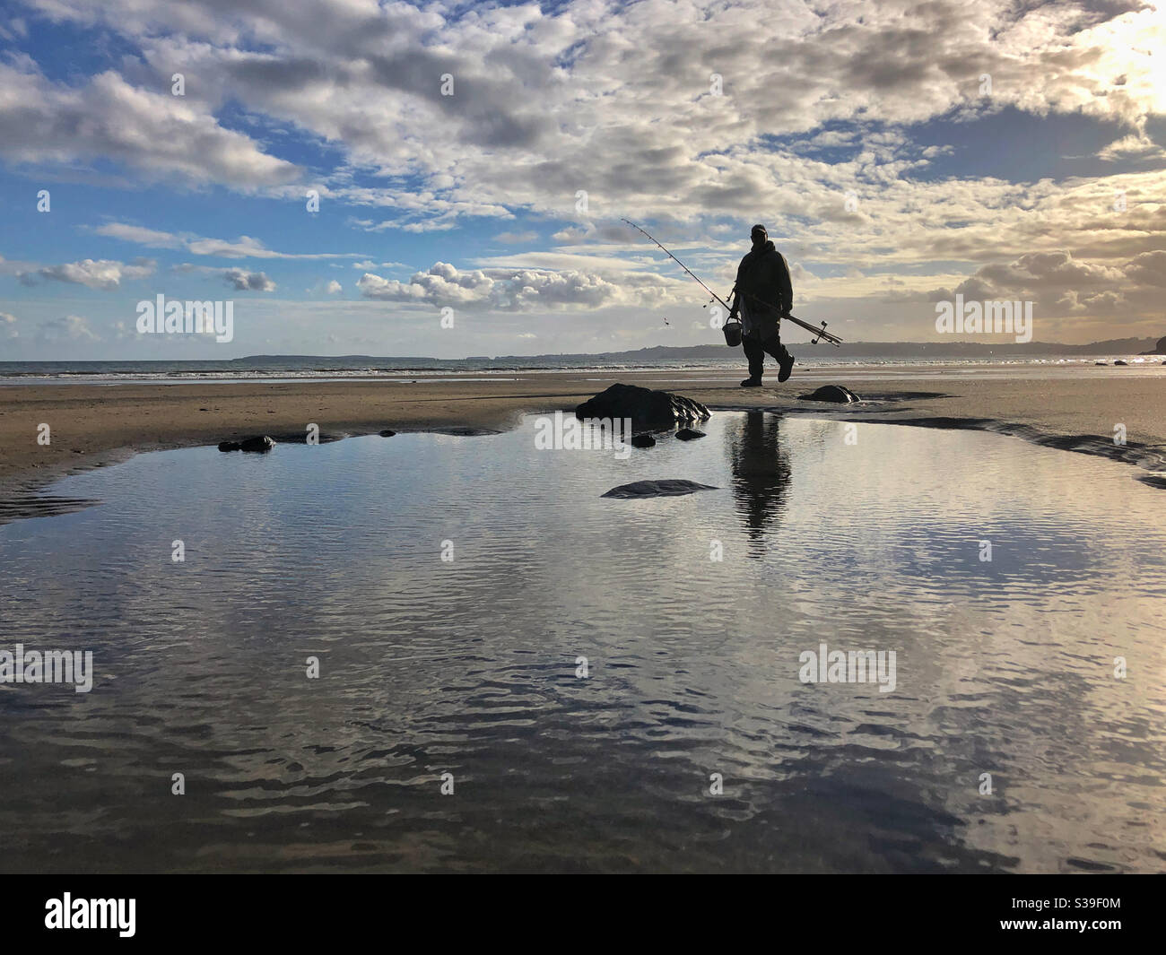 Ein Angler verlässt den Strand am Ende einer Angelsitzung. - Smartphone-aufgenommenes Stockfoto