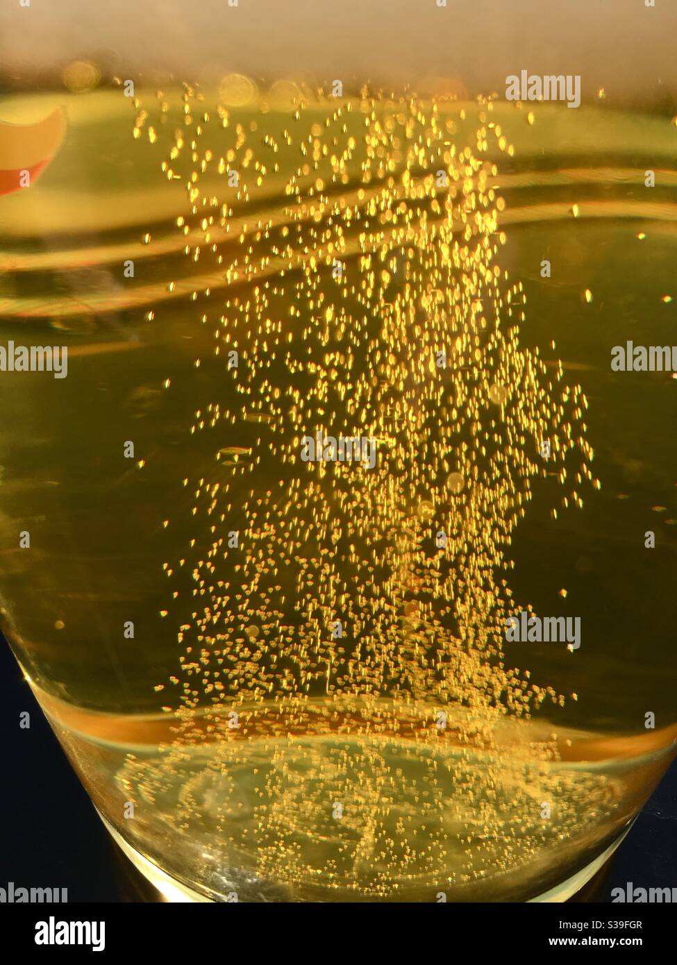 Golden Beer bläht durch ein Glas - Smartphone-aufgenommenes Stockfoto