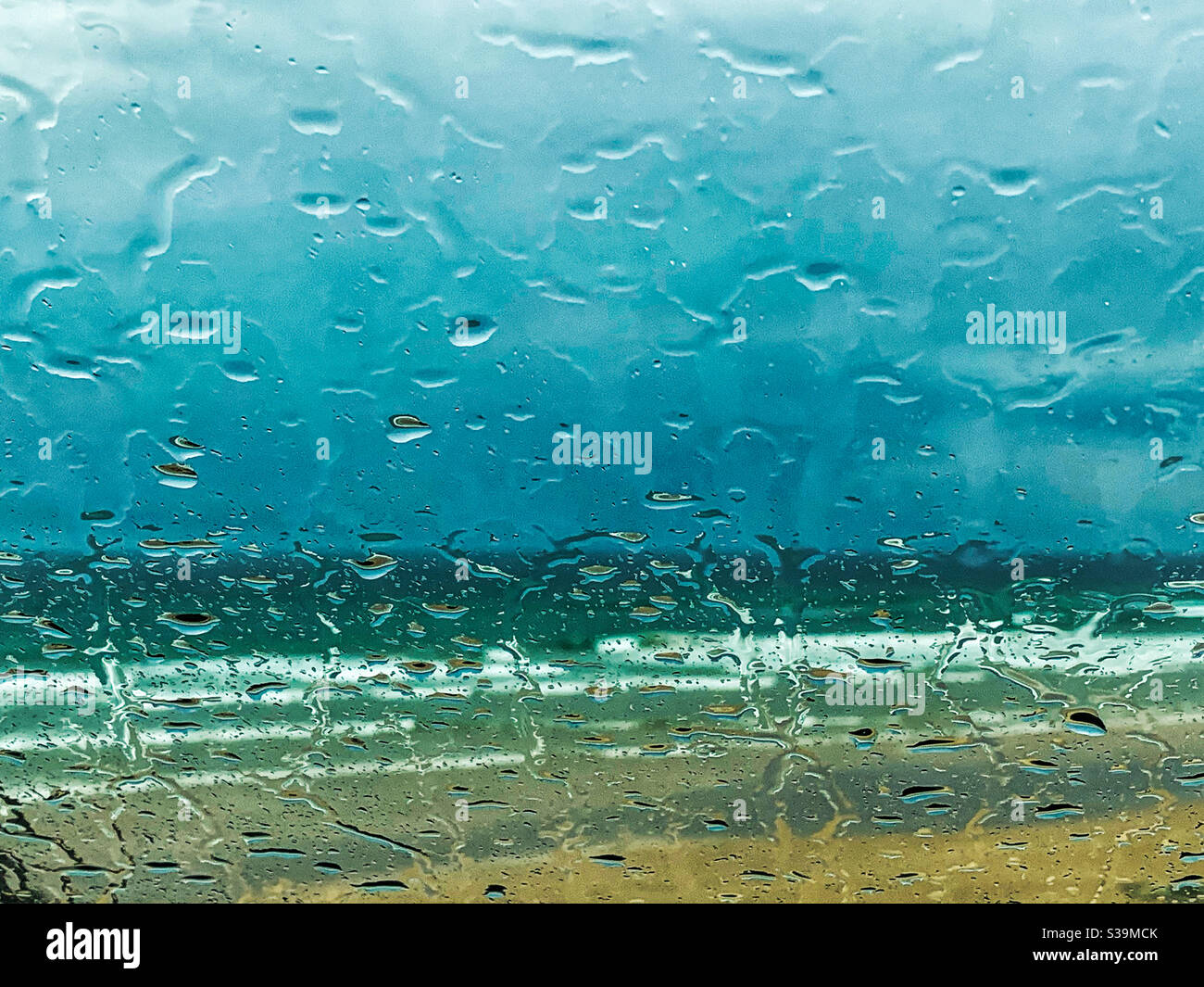 Regentage blau, Regentropfen auf Fensterscheiben am Strand Stockfoto