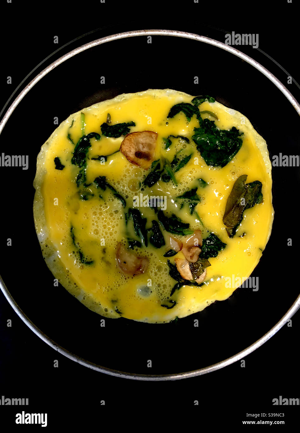 Eier kochen in einer Pfanne auf dem Herd mit Spinat und Champignons. Stockfoto