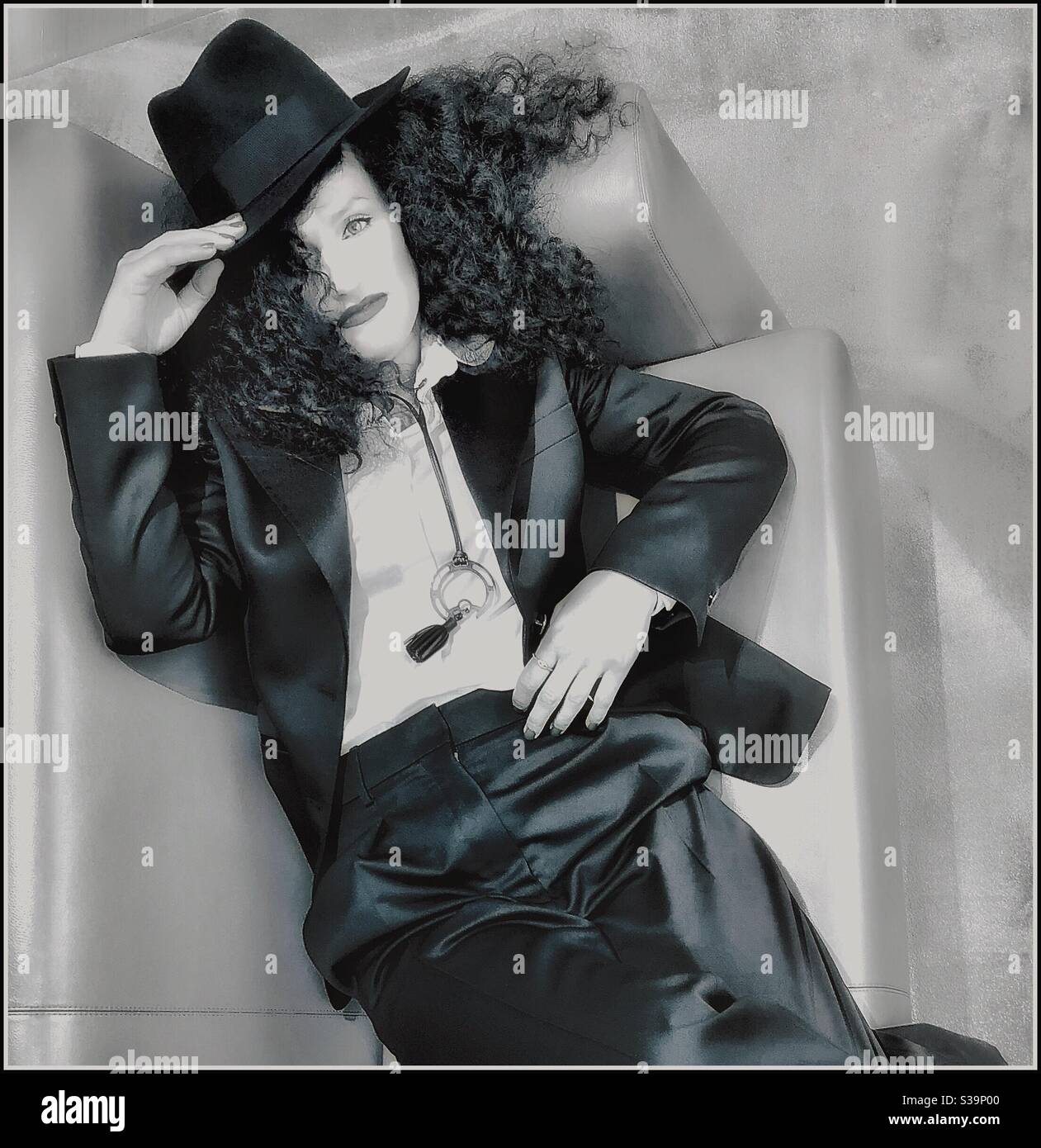 Eine junge Frau, die auf einem Sofa liegt und einen Smoking trägt. - Smartphone-aufgenommenes Stockfoto