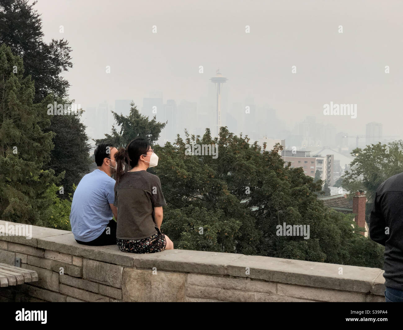 Seattle, USA. September 2020. Zwei Menschen mit K95-Masken sitzen im normalerweise malerischen Kerry Park, der Skyline der Stadt, die jetzt voller Wildfemrauch ist. Stockfoto