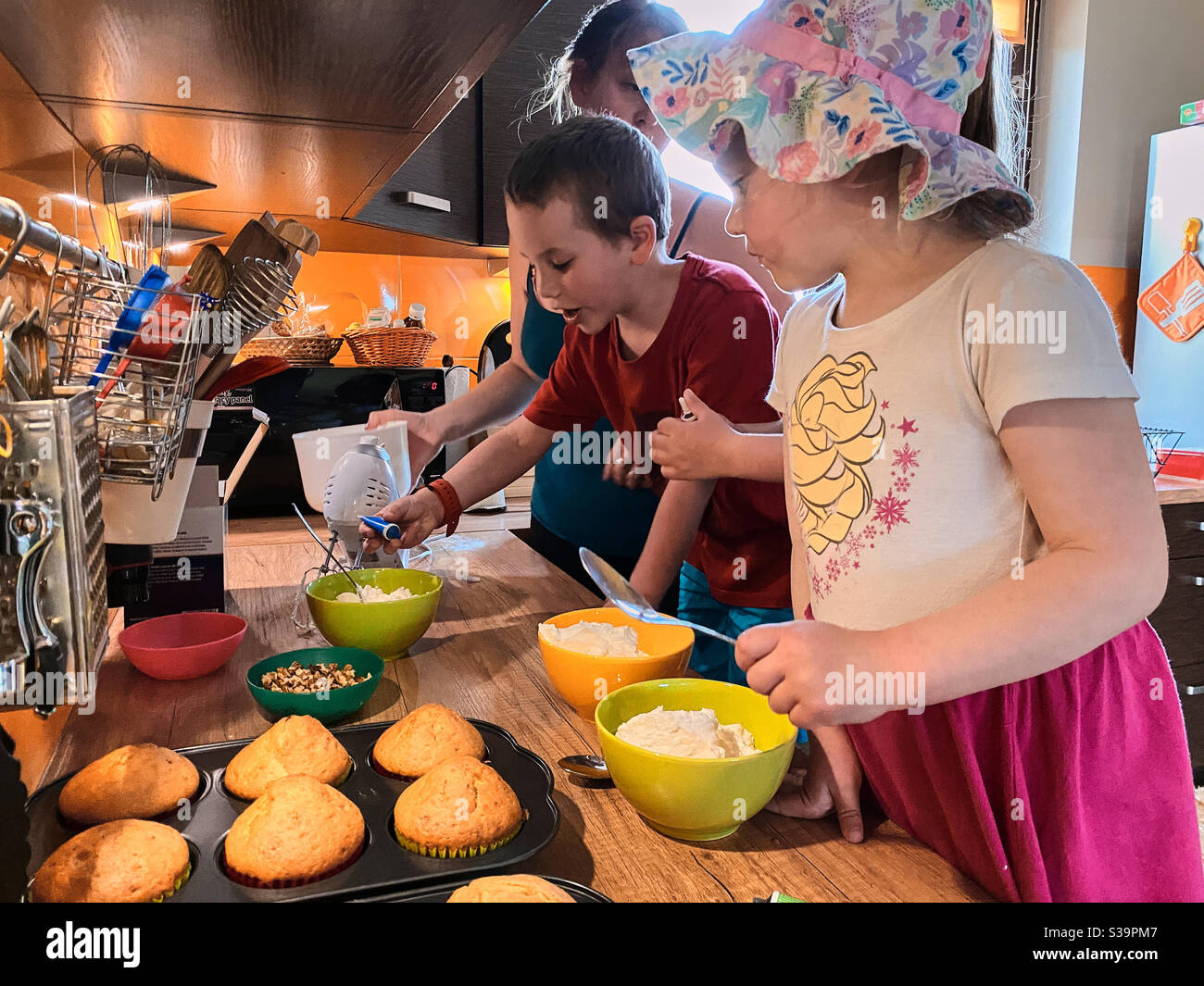 Gruppe von Kindern backen Cupcakes, Vorbereitung Zutaten, Toppings, Streuseln für die Dekoration Cookies. Kinder lernen zu kochen, arbeiten zusammen in der Küche zu Hause Stockfoto