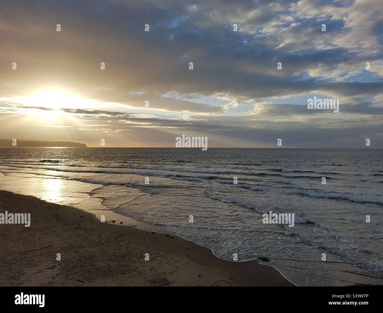 Sonnenuntergang und Sonnenstrahlen über Strand, goldene Farbe, Wellen, ruhiges Meer Stockfoto