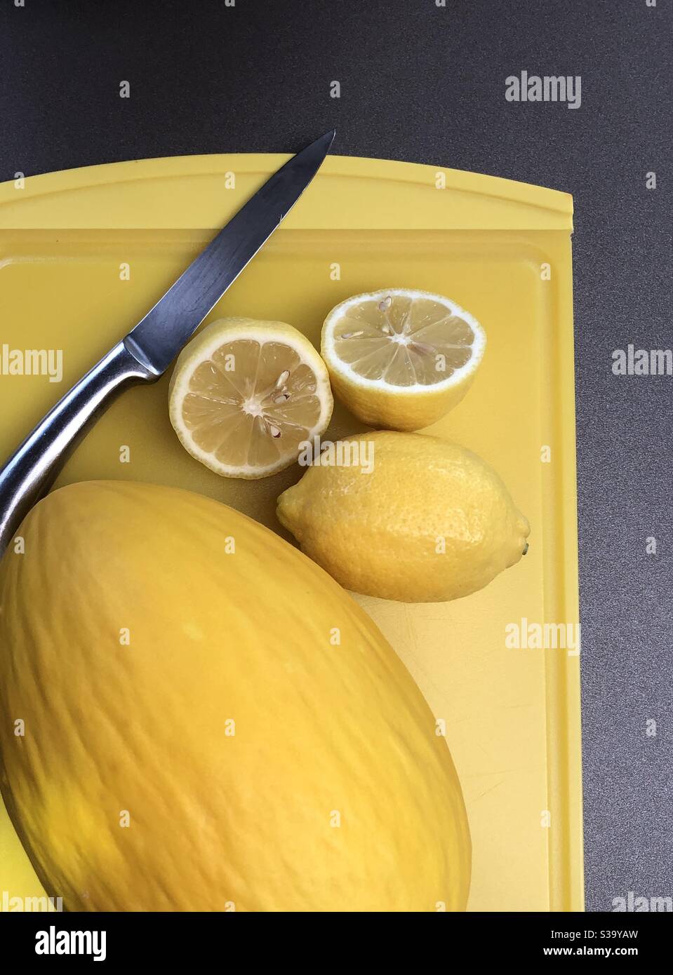 Melone und Zitronen auf einem gelben Brett - Smartphone-aufgenommenes Stockfoto