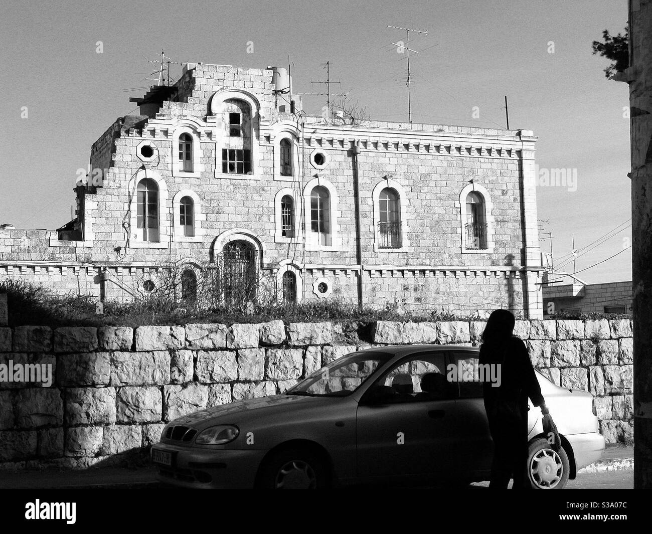 Ein altes Gebäude in Bethlehem und eine Frau daneben Ein Auto auf der Straße Stockfoto