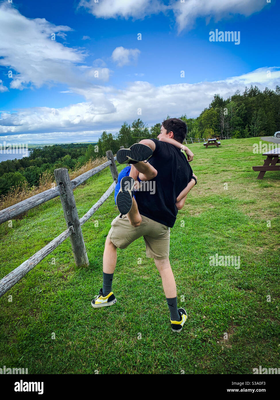 Ein Teenager-Bruder holt seinen jüngeren Bruder spielerisch an einem malerischen Aussichtspunkt entlang der I-95 in Maine ab. Stockfoto