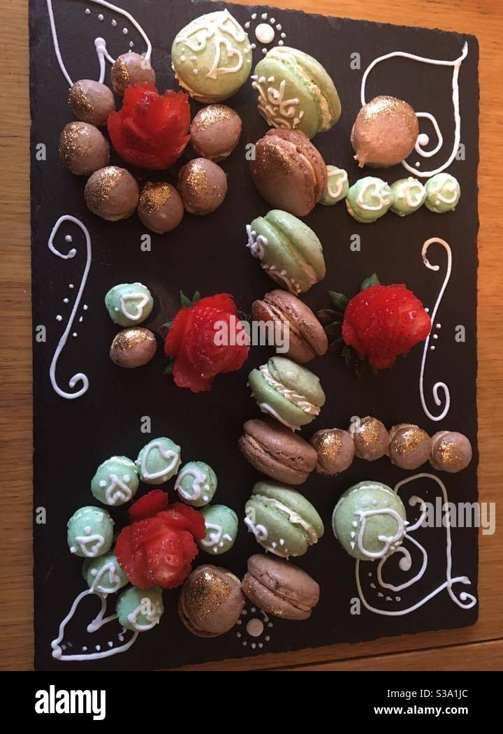 Macaron auf Schiefertafel mit Verzierung und Erdbeere angeordnet rosen Stockfoto