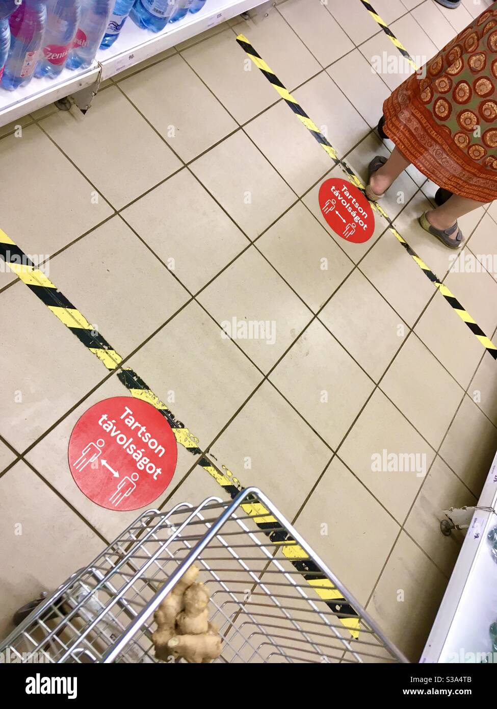 Halten Sie Distanzschilder auf dem Boden in Supermarkt, Sopron, Ungarn - Smartphone-aufgenommenes Stockfoto
