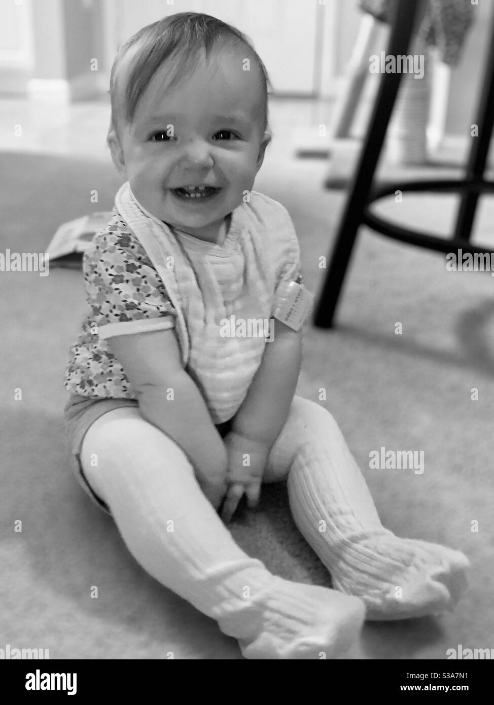 Baby lacht in weißen Strumpfhosen. Stockfoto