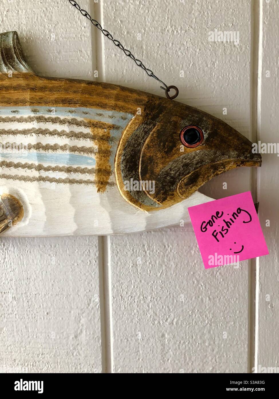 Hölzerne geschnitzte Fische auf einer Eingangshalle Wand mit einem Pfosten, den er "Gone Fishing" notiert. Stockfoto