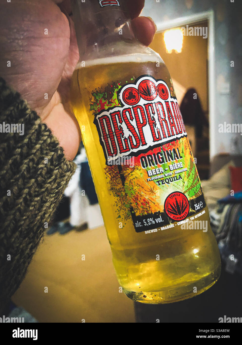 Eine männliche Hand hält eine Flasche Desperado Bier an einem Abend. Stockfoto