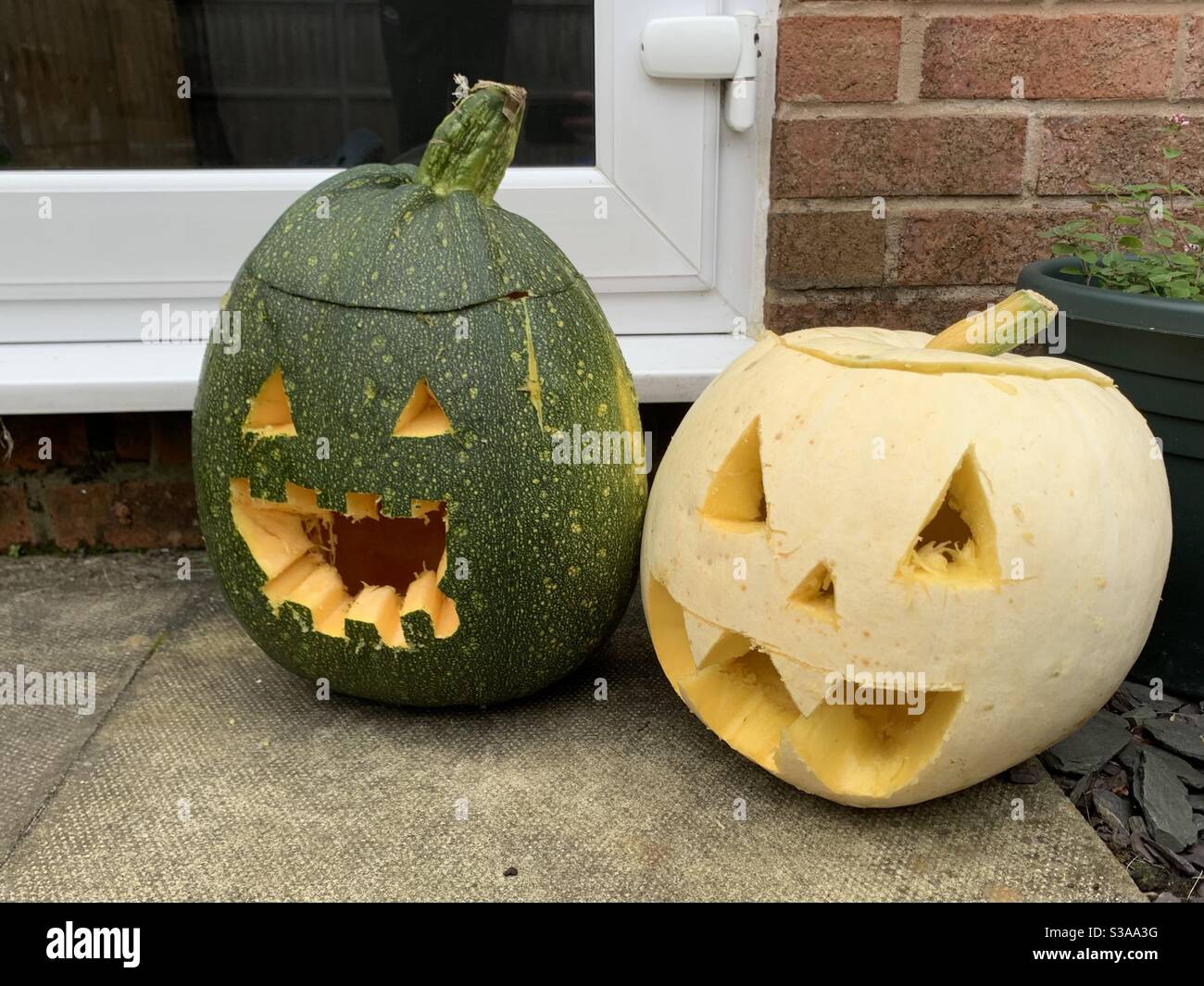 Kürbisgesichter. Grüner und weißer Kürbis. Halloween Kürbisse an der Tür. Stockfoto