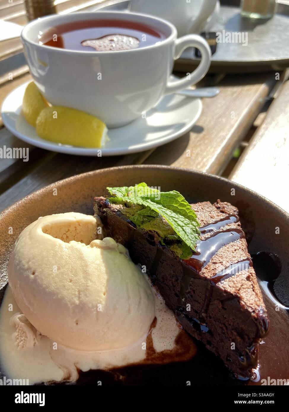 Schokoladenbrownie und Eis mit einer Tasse Tee mit Zitrone Stockfoto