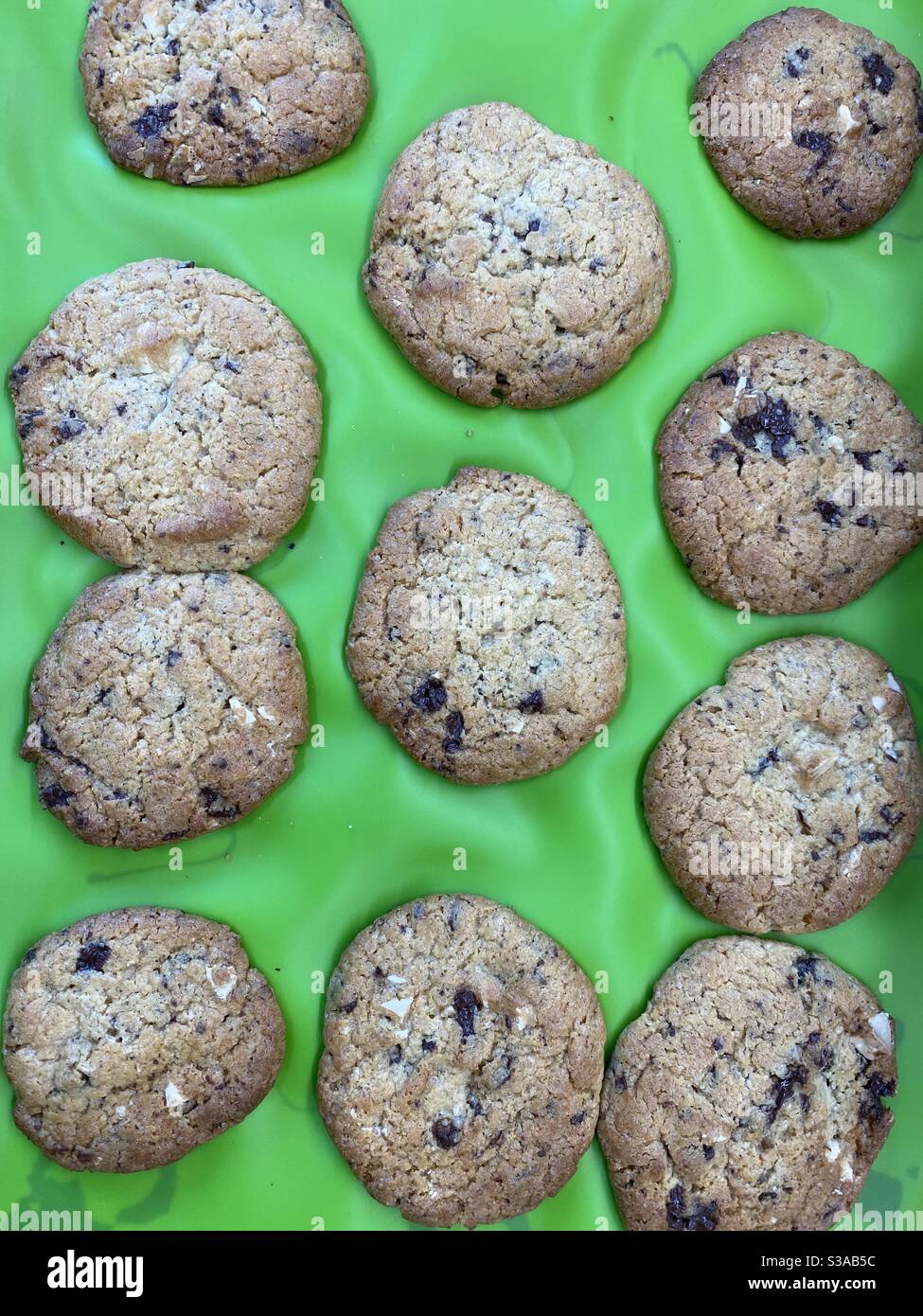 Chocolate Chip Kekse frisch aus dem Ofen auf einem grünen Silikonmatte Stockfoto